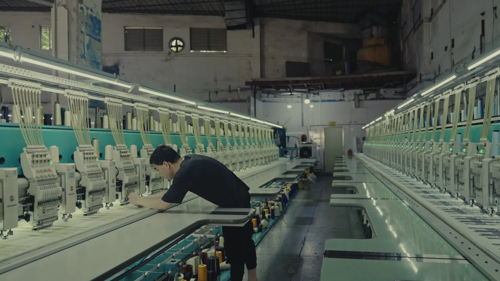 Embroidery production line in our Guangdong factory network, with an operator checking a bulk run