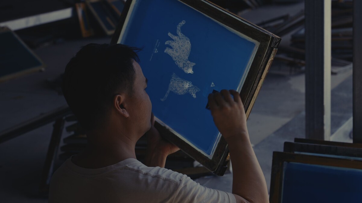 Worker checking and refining a screen-printing stencil
